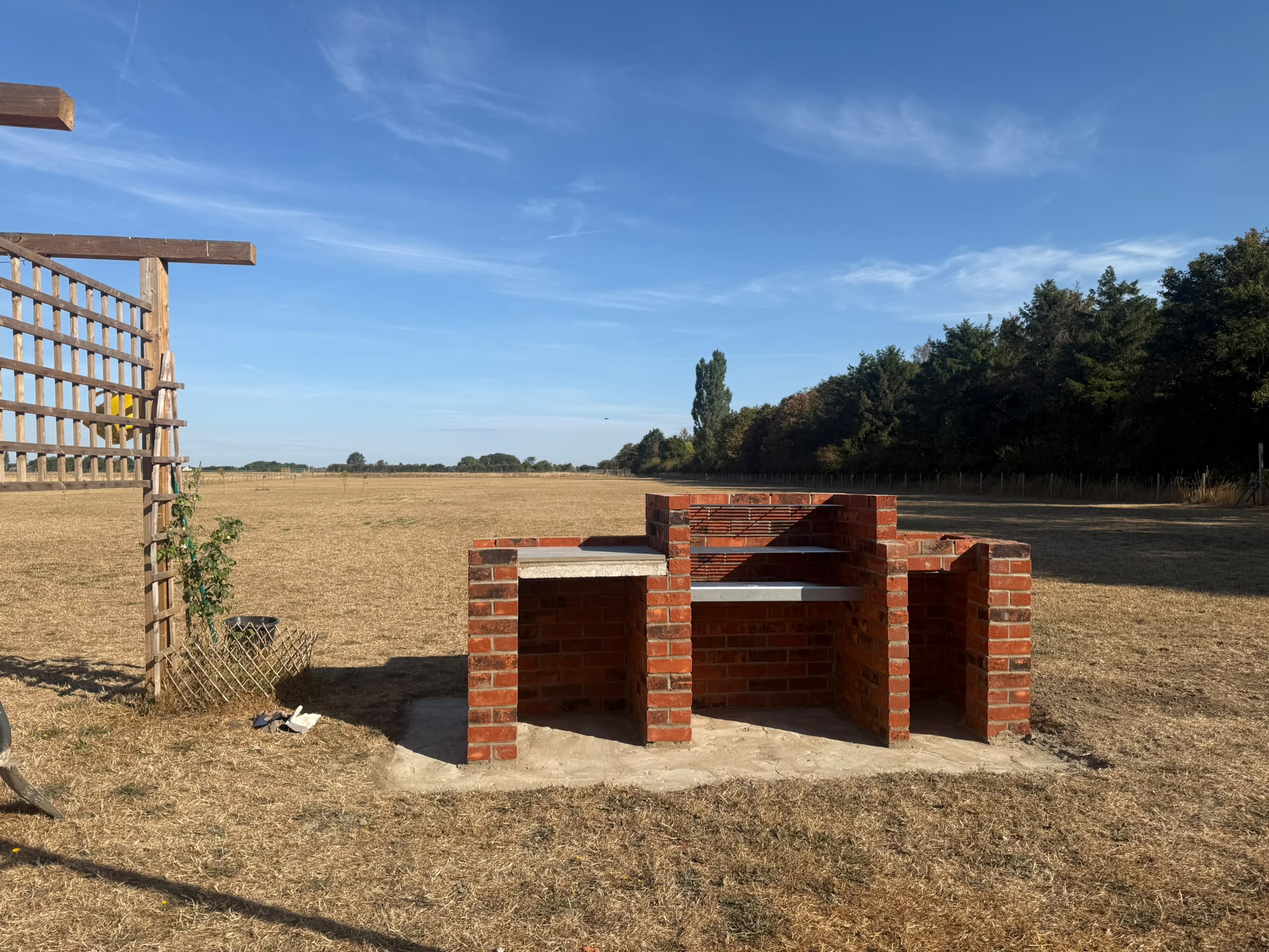 Brick outdoor kitchen and barbecue build in an open garden setting